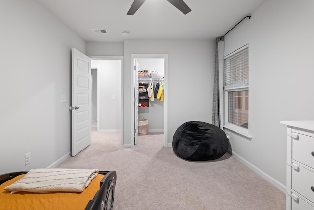 bedroom with a walk in closet, light carpet, a closet, and ceiling fan