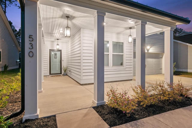 exterior entry at dusk with a porch and a garage