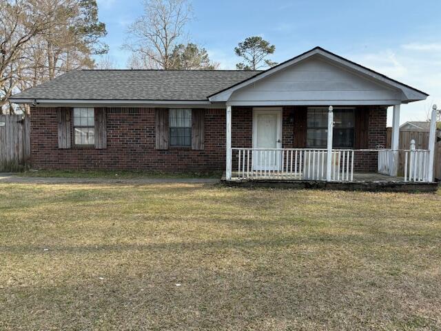 single story home with a front yard, fence, covered porch, and brick siding