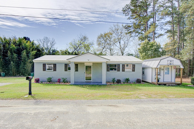 single story home with brick siding, an outdoor structure, a front lawn, and metal roof