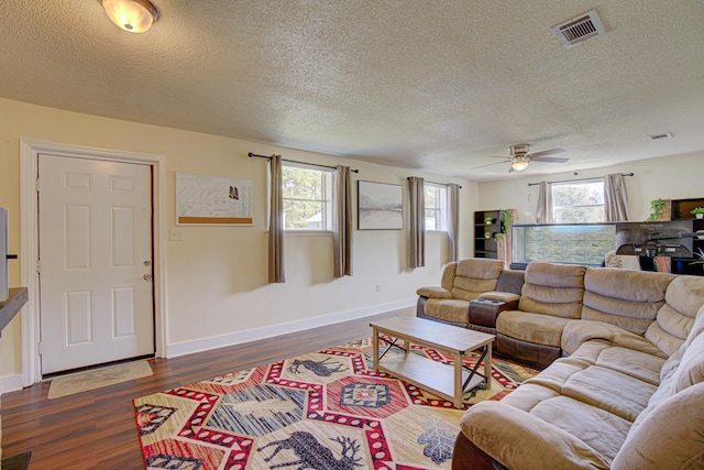 living area featuring a ceiling fan, a textured ceiling, visible vents, and plenty of natural light