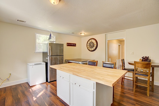 kitchen featuring dark wood-style flooring, visible vents, fridge, freestanding refrigerator, and butcher block countertops