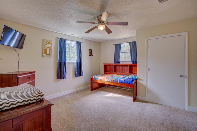 carpeted bedroom featuring baseboards, a textured ceiling, ceiling fan, and visible vents
