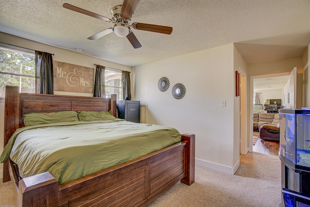 carpeted bedroom featuring baseboards, multiple windows, a ceiling fan, and a textured ceiling