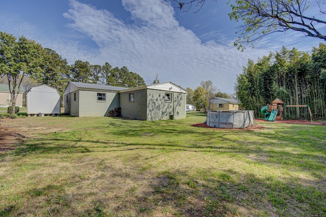 view of yard with an outbuilding, an outdoor pool, a playground, and a shed