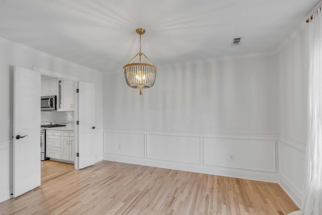 unfurnished dining area with visible vents, ornamental molding, light wood-style flooring, and an inviting chandelier