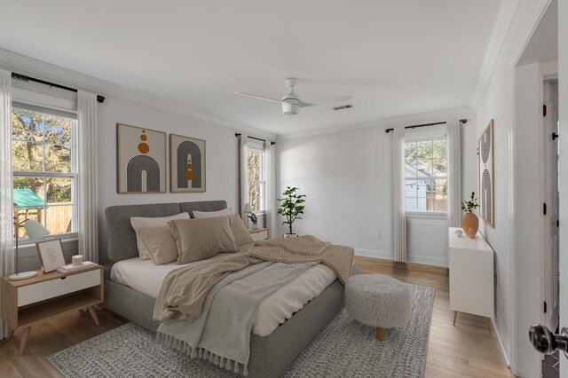 bedroom with ornamental molding, multiple windows, and light wood-style floors