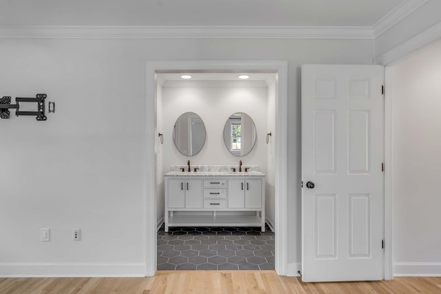 bathroom featuring double vanity, ornamental molding, a sink, and wood finished floors