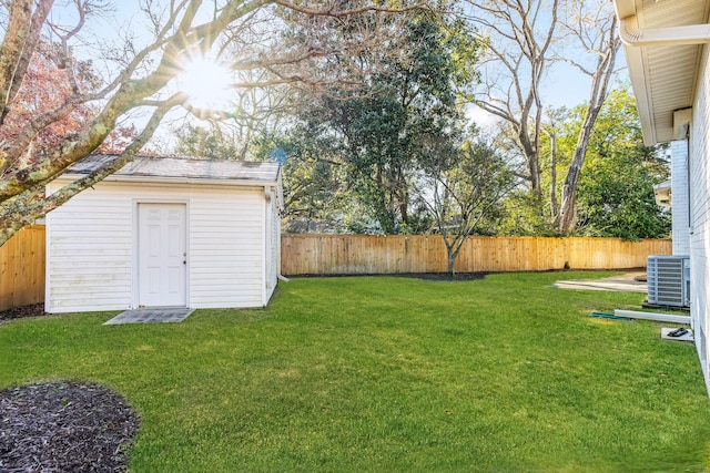 view of yard with an outbuilding, central AC, and a fenced backyard