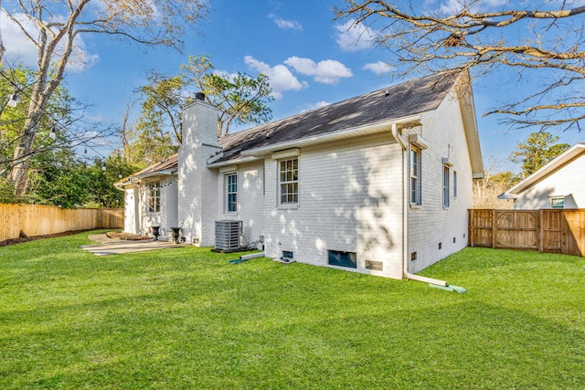 back of house featuring a patio, a yard, central AC, and a chimney