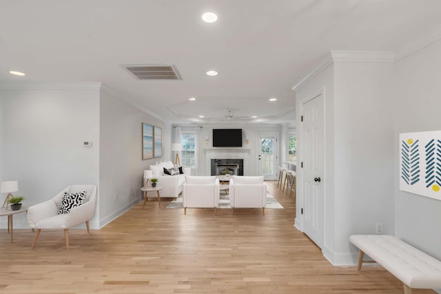 interior space with light wood finished floors, a fireplace, visible vents, and crown molding