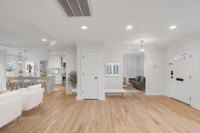 entryway featuring light wood-type flooring, visible vents, and crown molding