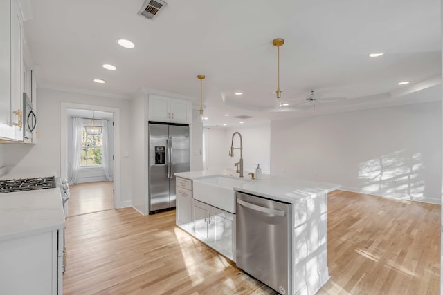 kitchen with a kitchen island with sink, appliances with stainless steel finishes, white cabinets, and a sink