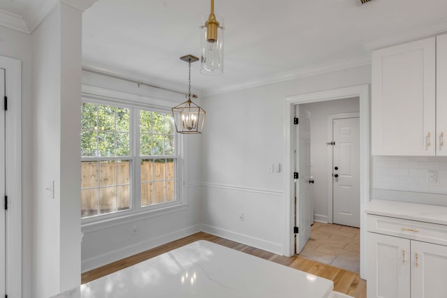 unfurnished dining area with ornamental molding, visible vents, light wood-style flooring, and baseboards