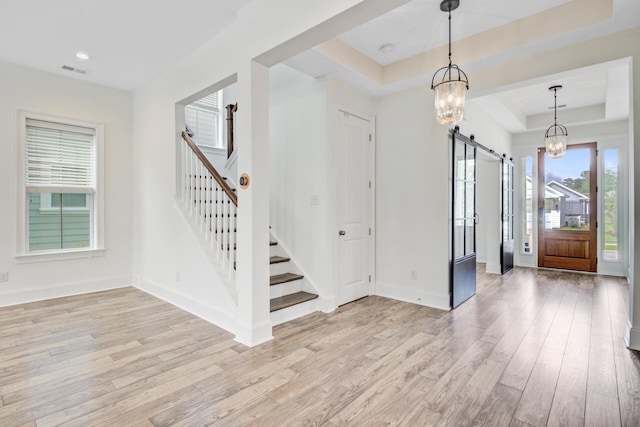 1485 Bourne Xing, Mount Pleasant, SC 29466 - entrance foyer with a barn door, a raised ceiling, stairs, a chandelier, and light wood-style flooring