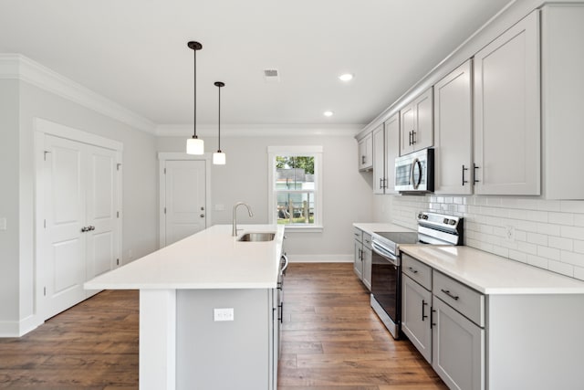 kitchen featuring sink, stainless steel appliances, crown molding, decorative light fixtures, and a kitchen island with sink