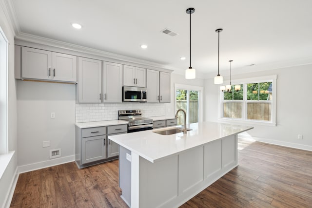 kitchen with sink, hanging light fixtures, tasteful backsplash, an island with sink, and appliances with stainless steel finishes