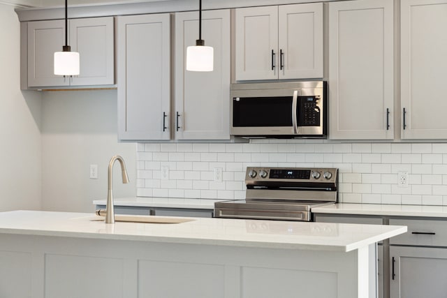 kitchen with backsplash, gray cabinets, pendant lighting, and appliances with stainless steel finishes