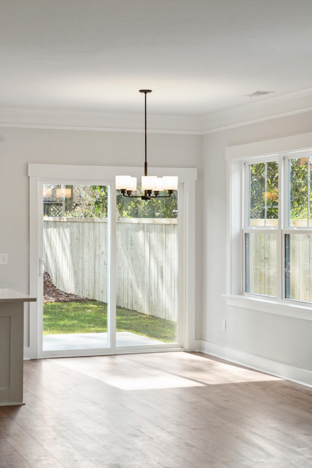 unfurnished dining area with light hardwood / wood-style floors, an inviting chandelier, and crown molding