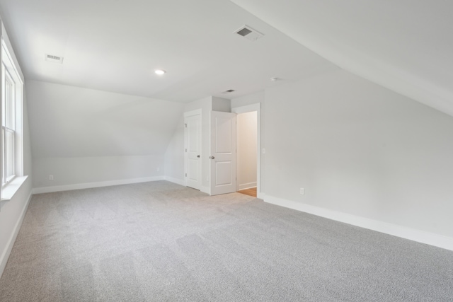 additional living space featuring light colored carpet and lofted ceiling