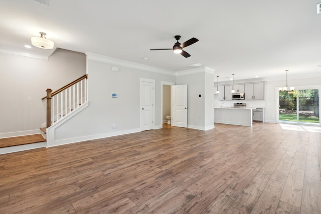 unfurnished living room featuring crown molding, wood-type flooring, and ceiling fan with notable chandelier