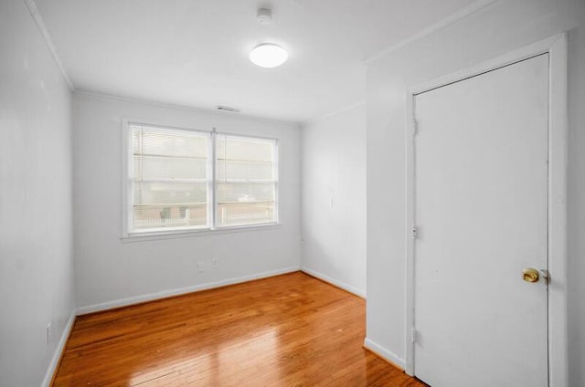 empty room with ornamental molding and light wood-type flooring