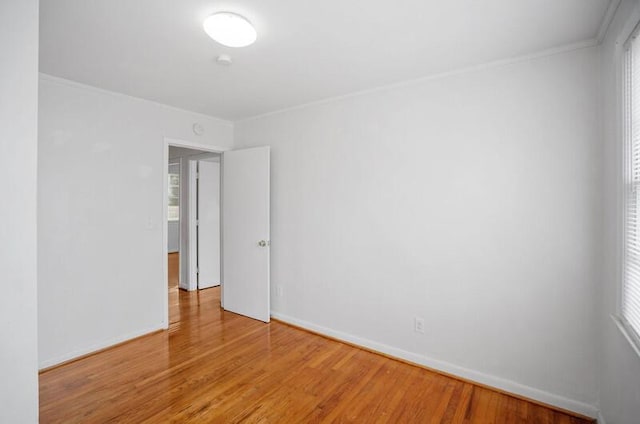 empty room featuring hardwood / wood-style flooring, a wealth of natural light, and ornamental molding