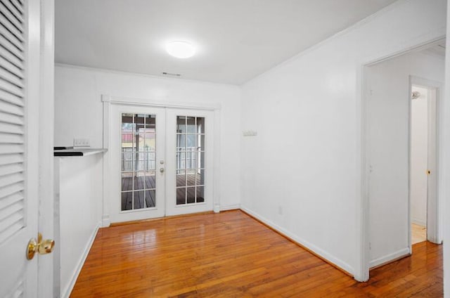 empty room with hardwood / wood-style flooring, ornamental molding, and french doors