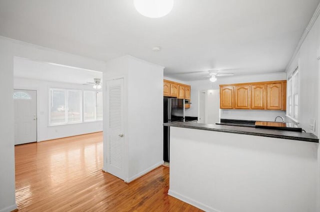 kitchen with black refrigerator, ceiling fan, kitchen peninsula, and light wood-type flooring