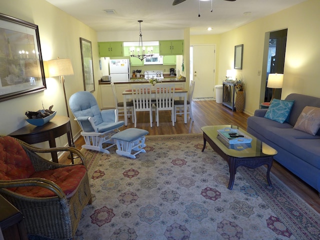 living room featuring hardwood / wood-style floors and ceiling fan with notable chandelier