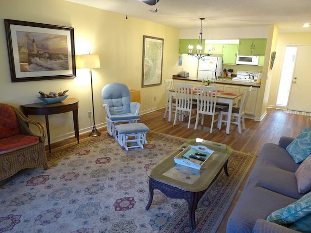 living room featuring ceiling fan with notable chandelier and hardwood / wood-style flooring