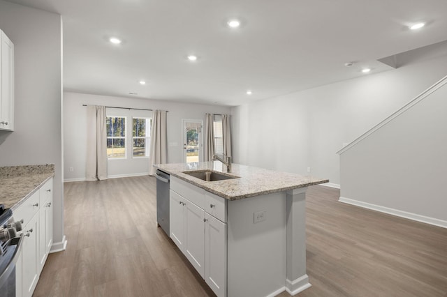 kitchen with white cabinetry, sink, light stone countertops, a kitchen island with sink, and appliances with stainless steel finishes