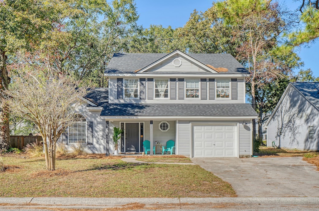 view of front property featuring a porch, a garage, and a front lawn