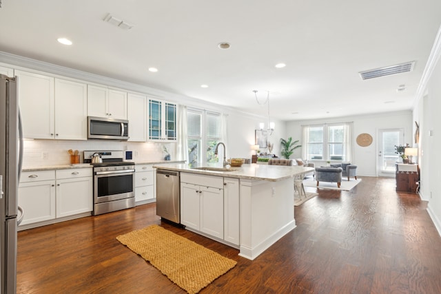 kitchen featuring dark wood-type flooring, sink, an island with sink, appliances with stainless steel finishes, and white cabinetry