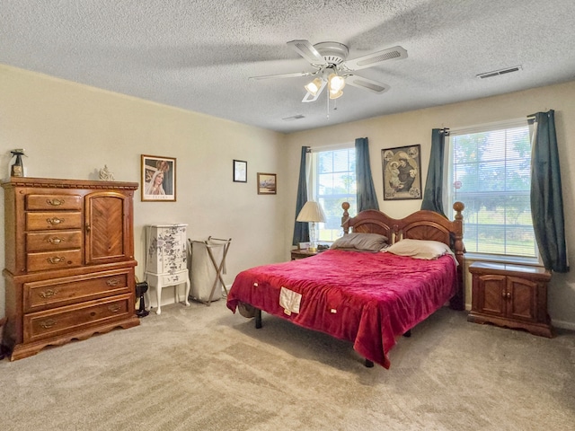 bedroom featuring a textured ceiling, light carpet, multiple windows, and ceiling fan