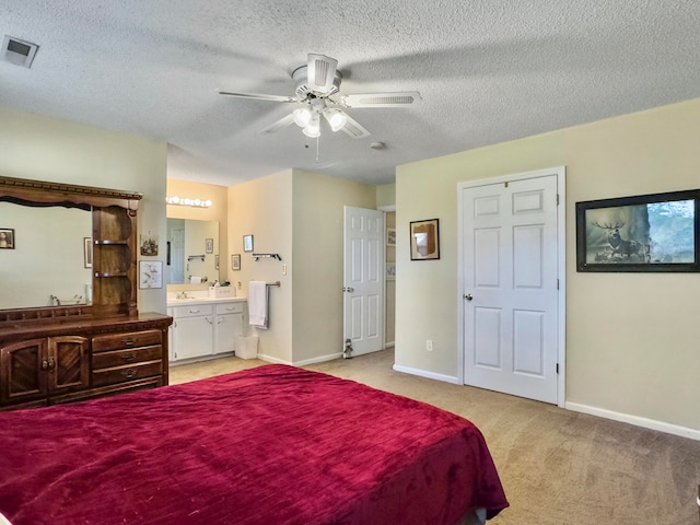 carpeted bedroom featuring ceiling fan, ensuite bath, sink, and a textured ceiling