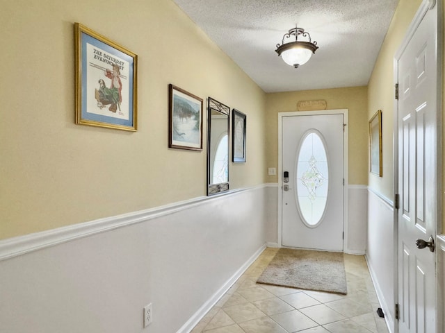 doorway to outside featuring a textured ceiling and light tile patterned floors