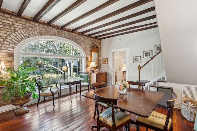 dining space featuring wood-type flooring, stairs, and beam ceiling