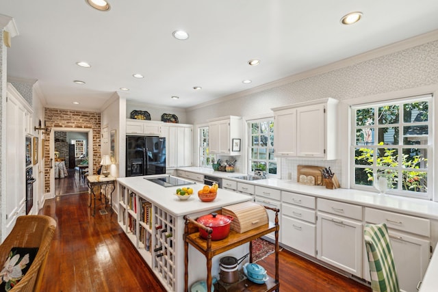 kitchen with a sink, black appliances, ornamental molding, and a kitchen island