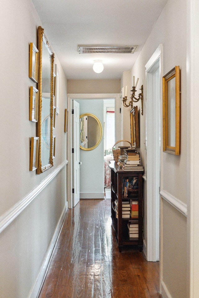 hall with wood-type flooring, visible vents, and baseboards