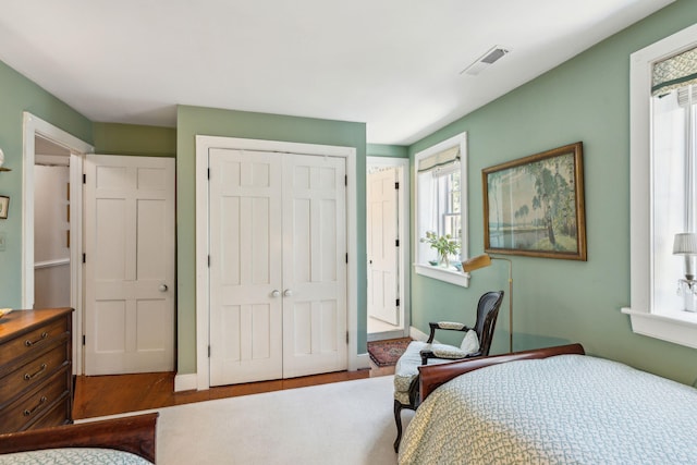 bedroom featuring a closet, wood finished floors, visible vents, and baseboards