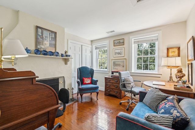 office area with hardwood / wood-style flooring, baseboards, a fireplace, and visible vents