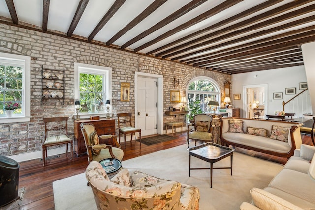 living area with hardwood / wood-style floors, brick wall, stairs, and beam ceiling