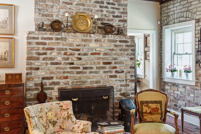 sitting room featuring a brick fireplace and brick wall