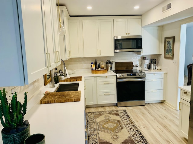 1202 Ventura Pl, Mount Pleasant, SC 29464 - kitchen featuring white cabinetry, light wood finished floors, stainless steel appliances, and tasteful backsplash