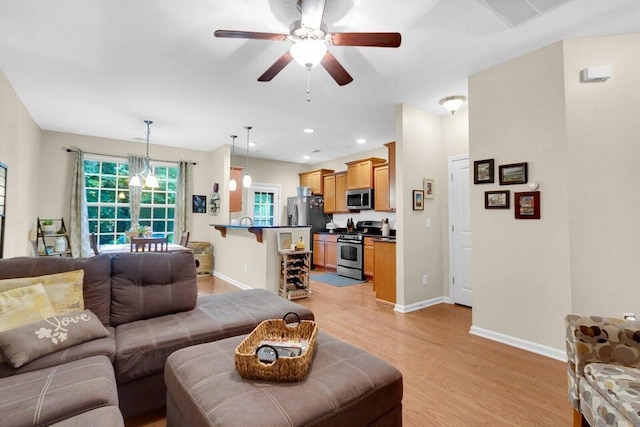 living room with ceiling fan and light hardwood / wood-style flooring