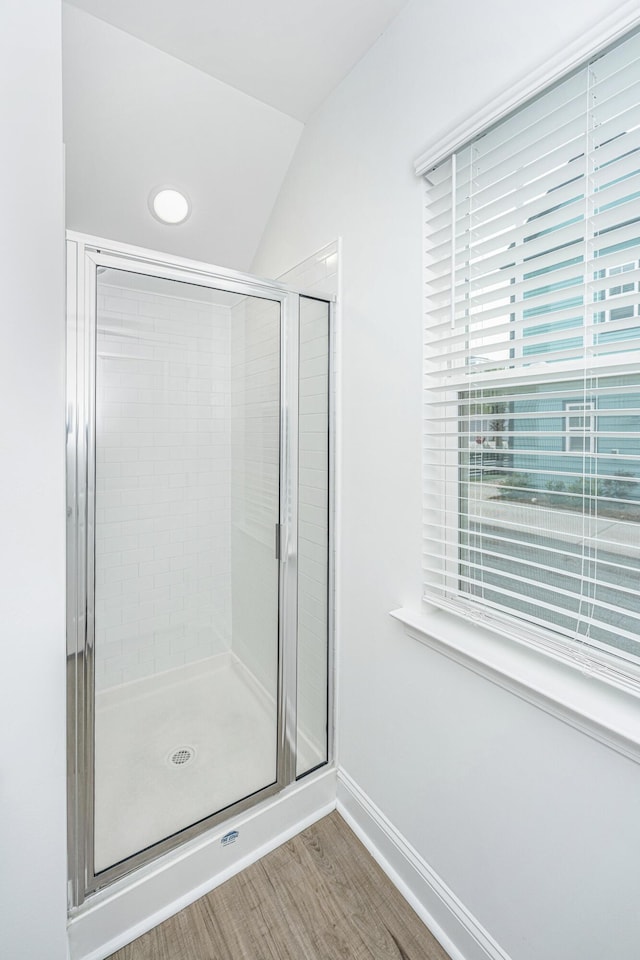 bathroom with hardwood / wood-style floors, a shower with door, and vaulted ceiling