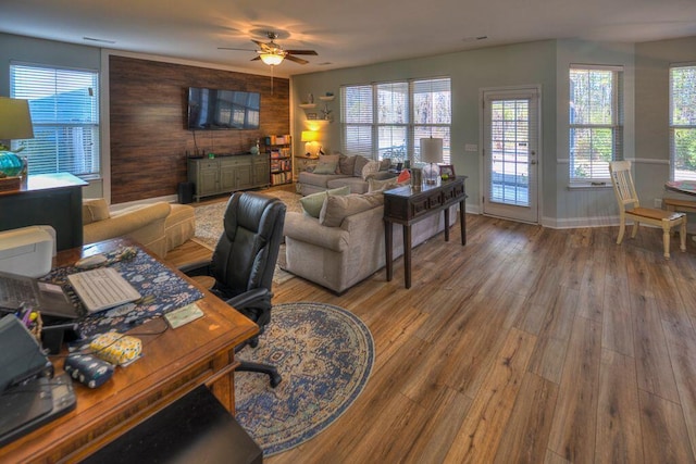 living room with ceiling fan, wooden walls, and hardwood / wood-style floors