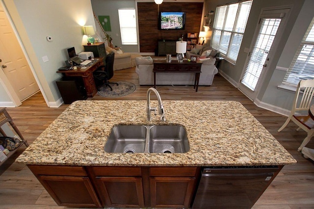 kitchen with hardwood / wood-style floors, light stone countertops, sink, and dishwasher