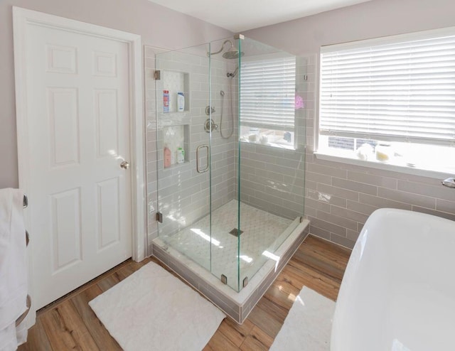 bathroom with tile walls, wood-type flooring, and shower with separate bathtub